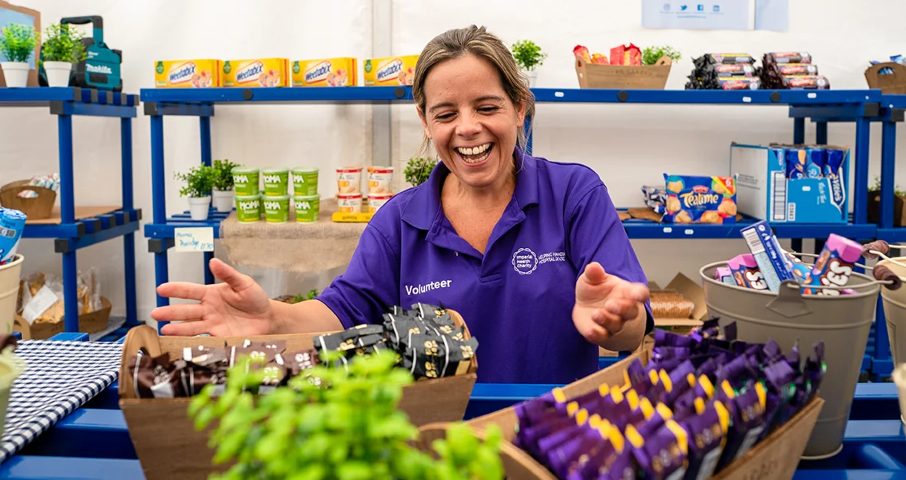 A woman smiling whilst sorting donations of food at a food bank
